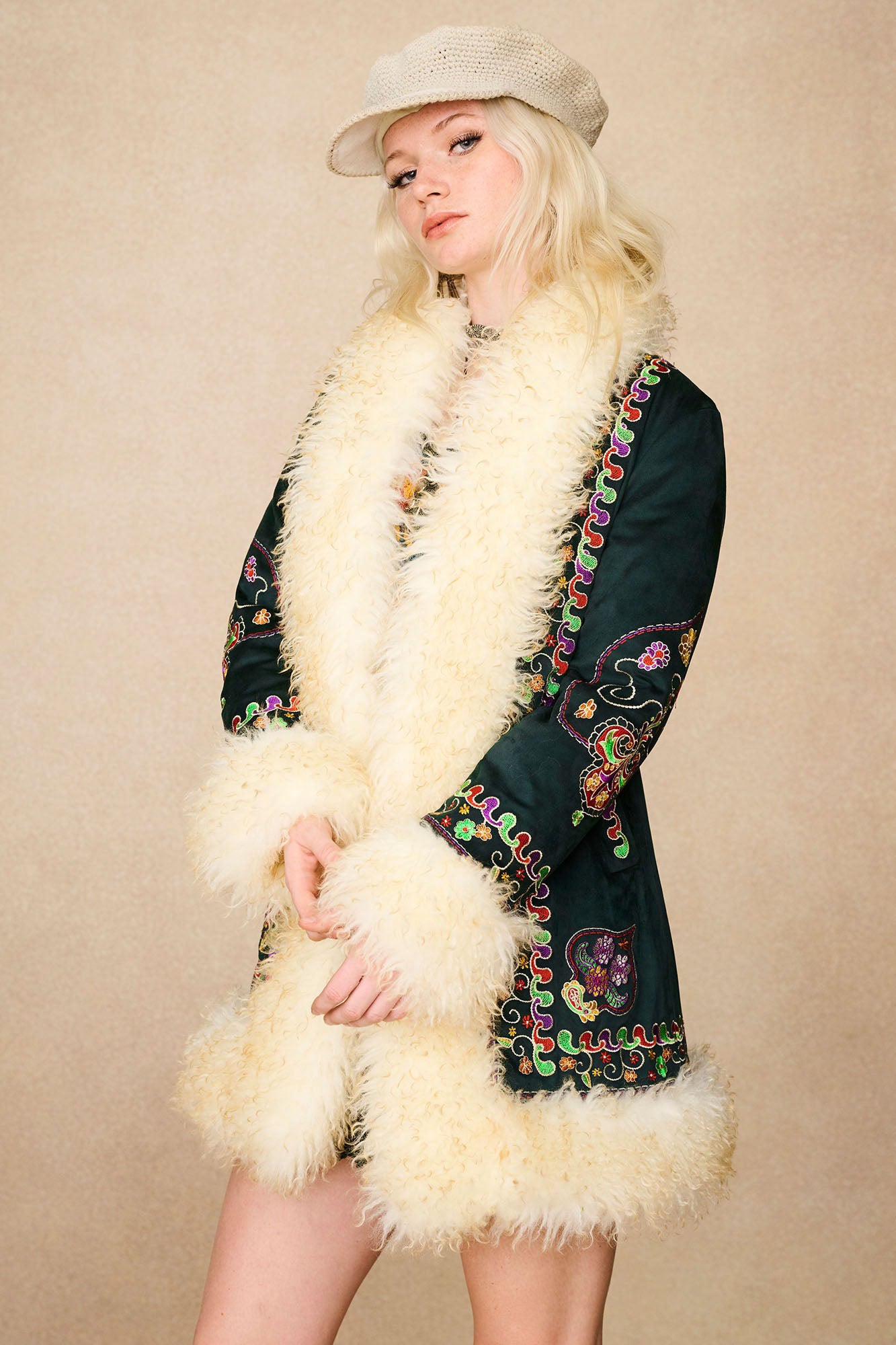 Model wearing The Hippie Shake's green embroidered Penny Lane coat with hands held loosely at the front.