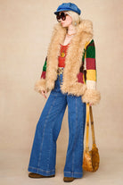 Model wearing The Hippie Shake's chevron flared denim jeans with patchwork coat, red crochet top and tan bag.