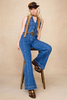 Model seated wearing The Hippie Shake’s brown panelled baker hat, styled with double denim and embroidered boots.
