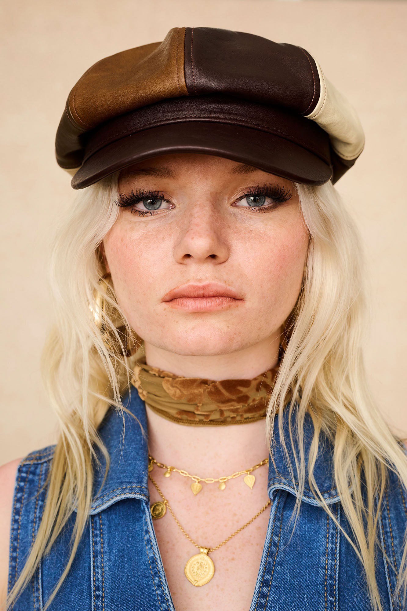 The Hippie Shake’s brown panelled baker hat with cream and tan sections, styled with gold pendants and a velvet neck scarf.
