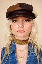 The Hippie Shake’s brown panelled baker hat with cream and tan sections, styled with gold pendants and a velvet neck scarf.