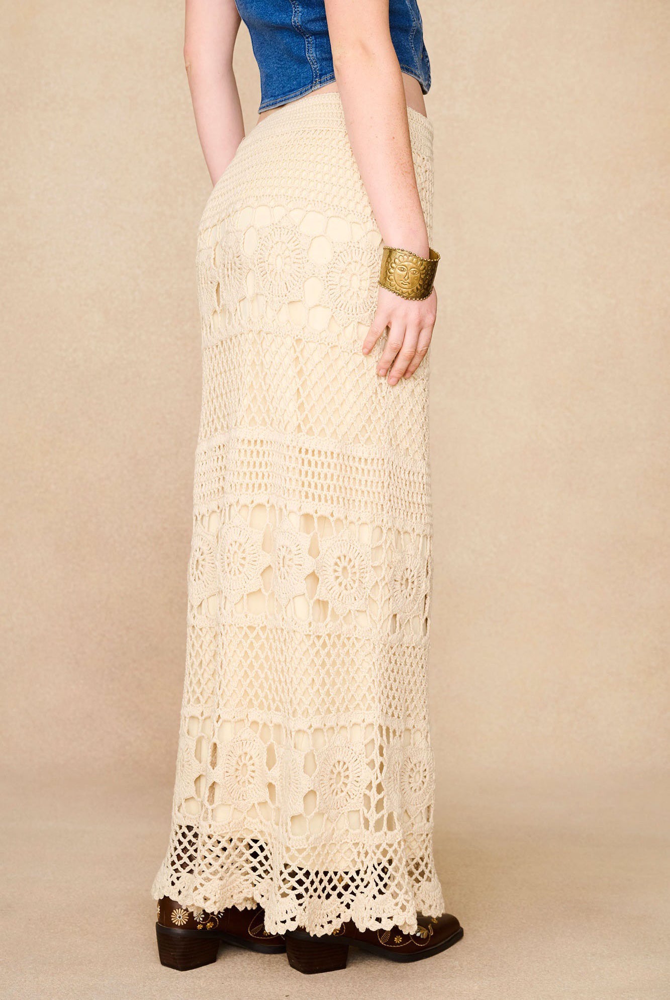 Side view of The Hippie Shake's cream crochet maxi skirt highlighting fitted shape and bold crochet textures.
