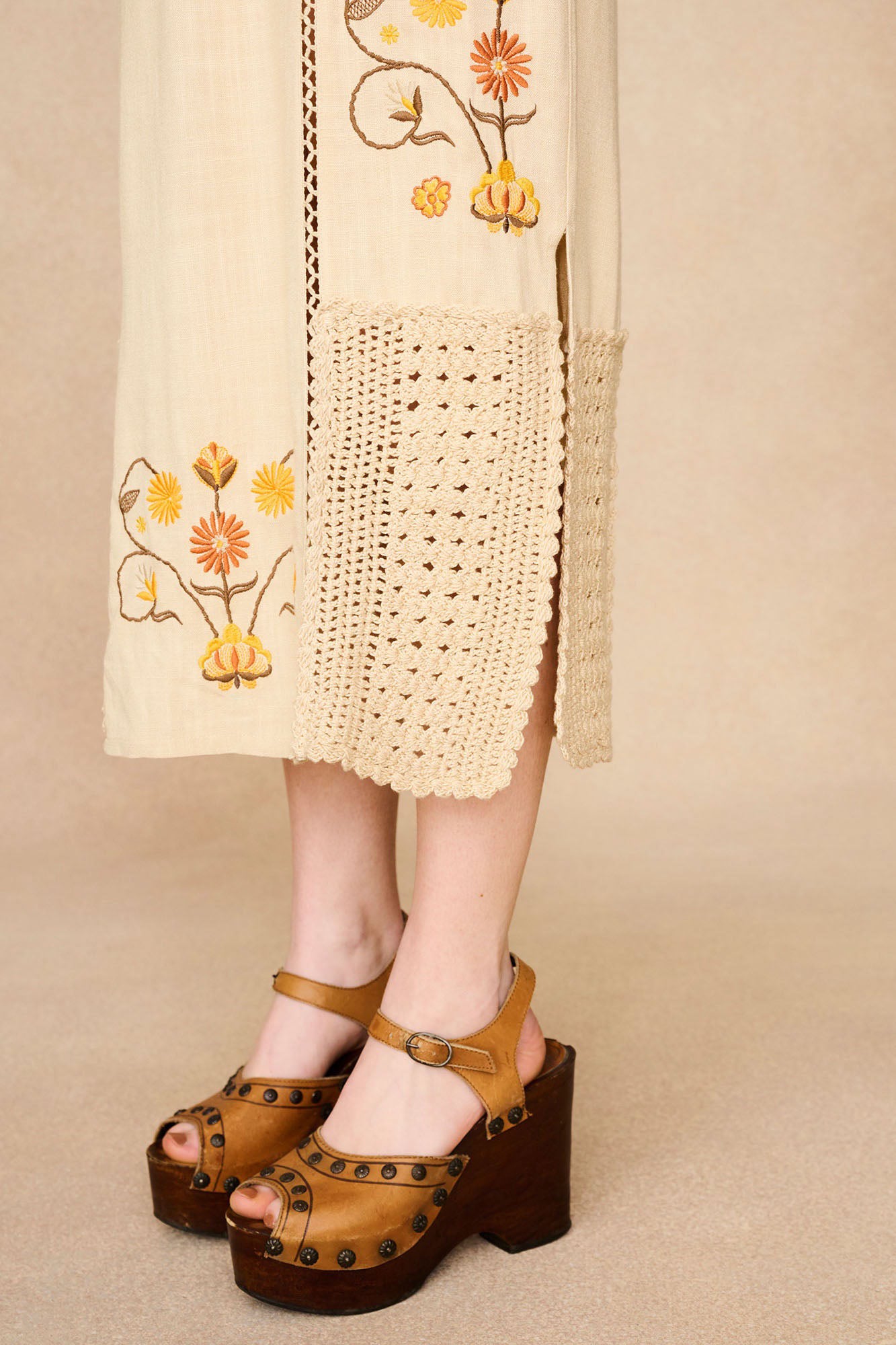 Close-up of The Hippie Shake's cream crochet trim midi dress showcasing the intricate floral embroidery and crochet trim below the knee.