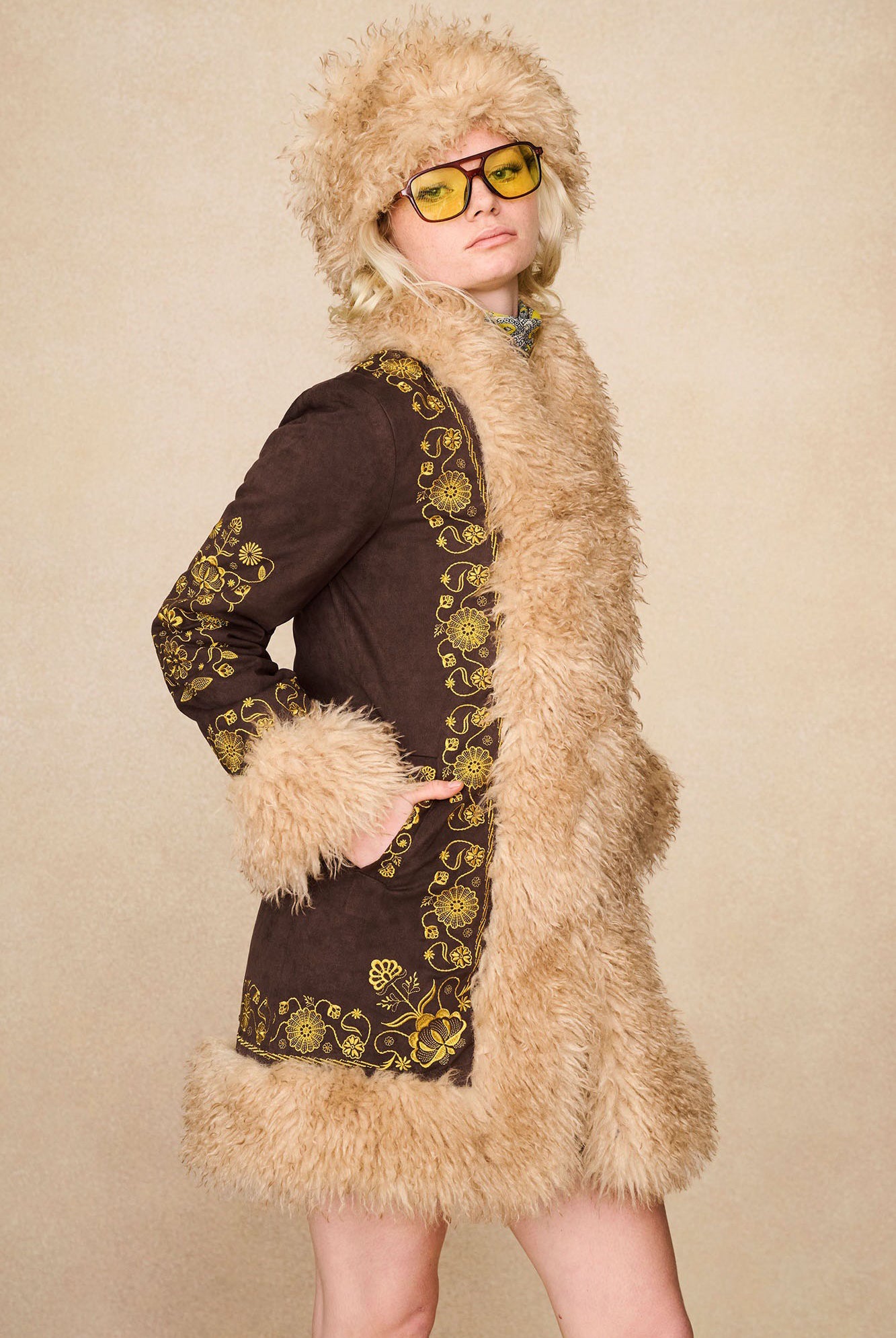 Model wearing The Hippie Shake's brown embroidered Penny Lane coat with our 70s style faux fur trim hat and yellow sunglasses.