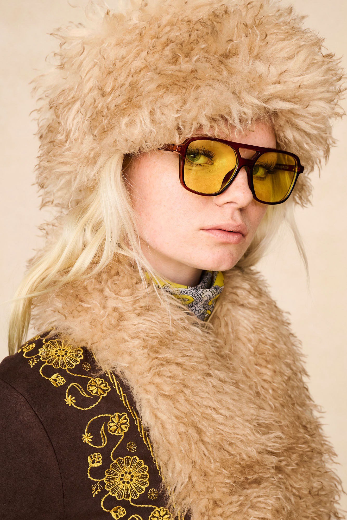 Close-up of model wearing The Hippie Shake's 70s inspired brown faux fur hat with our brown embroidered Penny Lane coat.