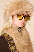 Close-up of model wearing The Hippie Shake's 70s inspired brown faux fur hat with our brown embroidered Penny Lane coat.