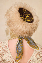 Back view of The Hippie Shake's brown faux fur hat with gold embroidery, styled with our cream crochet top and a mustard floral neck scarf.