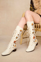 Model wearing The Hippie Shake's 70s style Penny Lane boots while seated in a wicker chair.