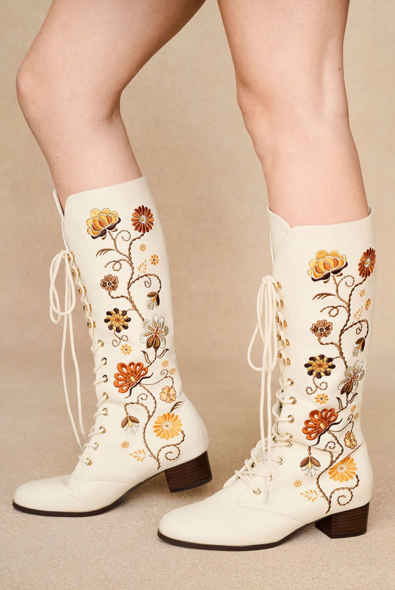 The Hippie Shake's cream Penny Lane embroidered floral boots with lace-up front and orange floral stitching.