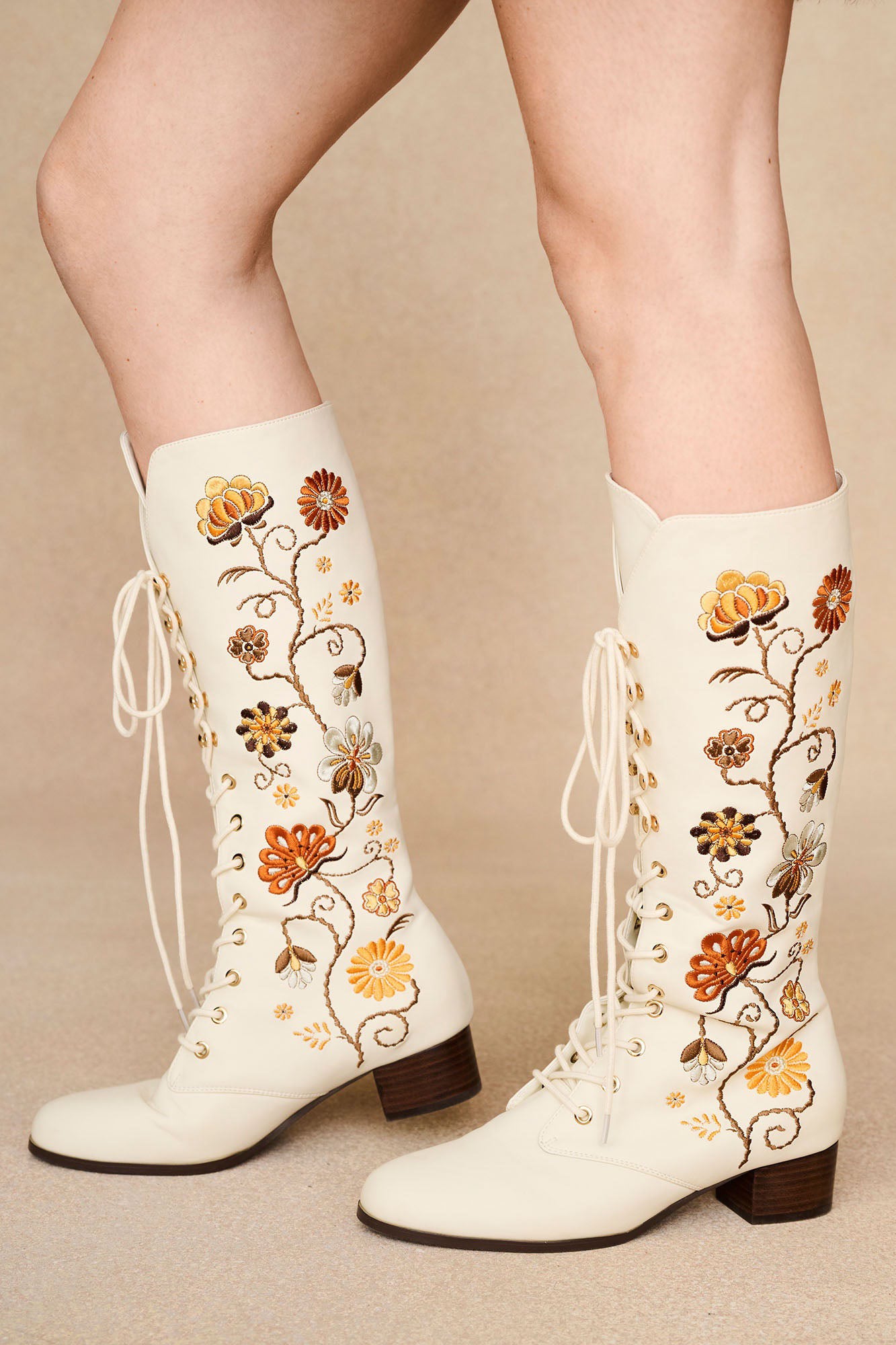 The Hippie Shake's cream Penny Lane embroidered floral boots with lace-up front and orange floral stitching.