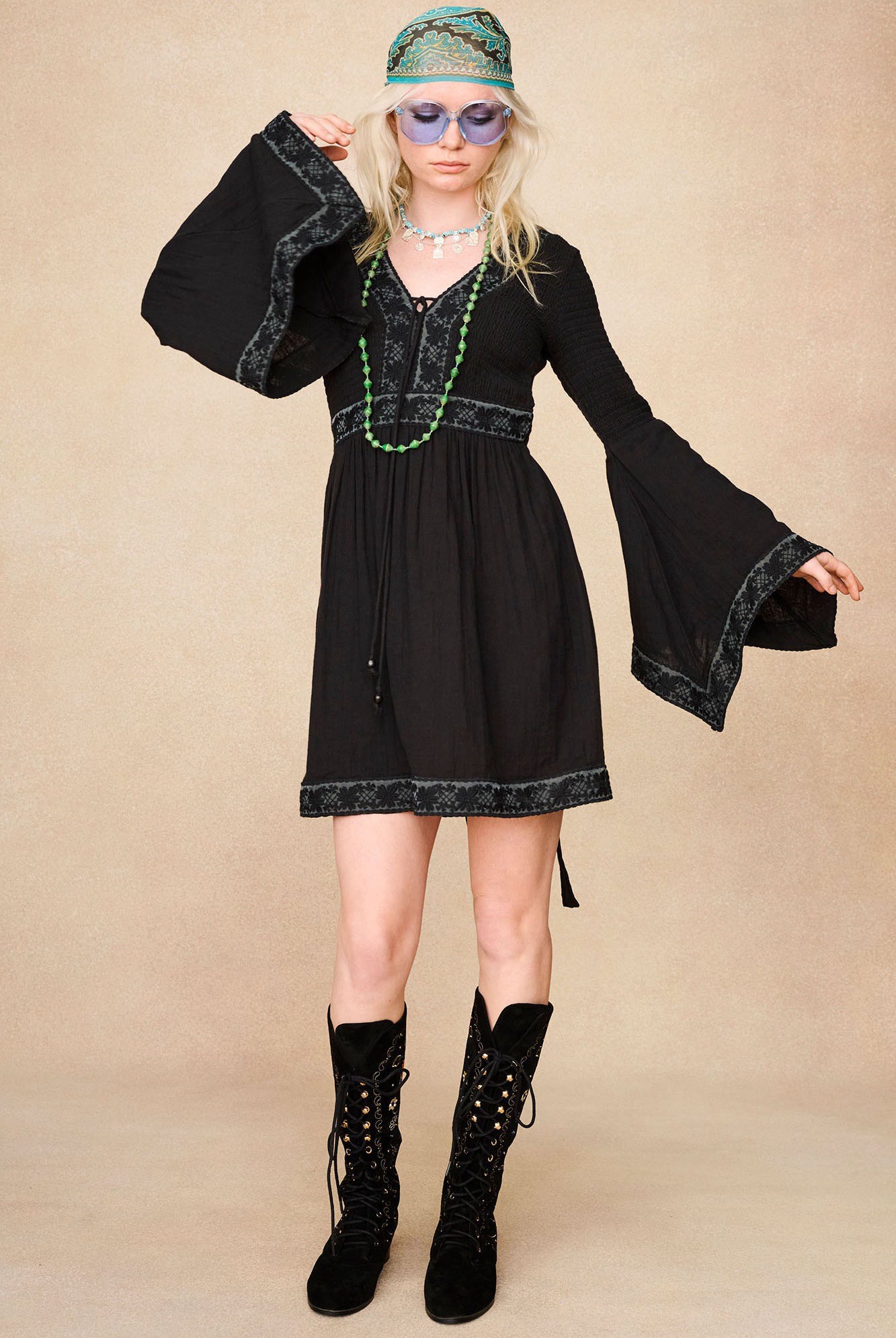 Full-length model shot featuring The Hippie Shake's black mini dress with lace trim styled with our black embroidered boots.