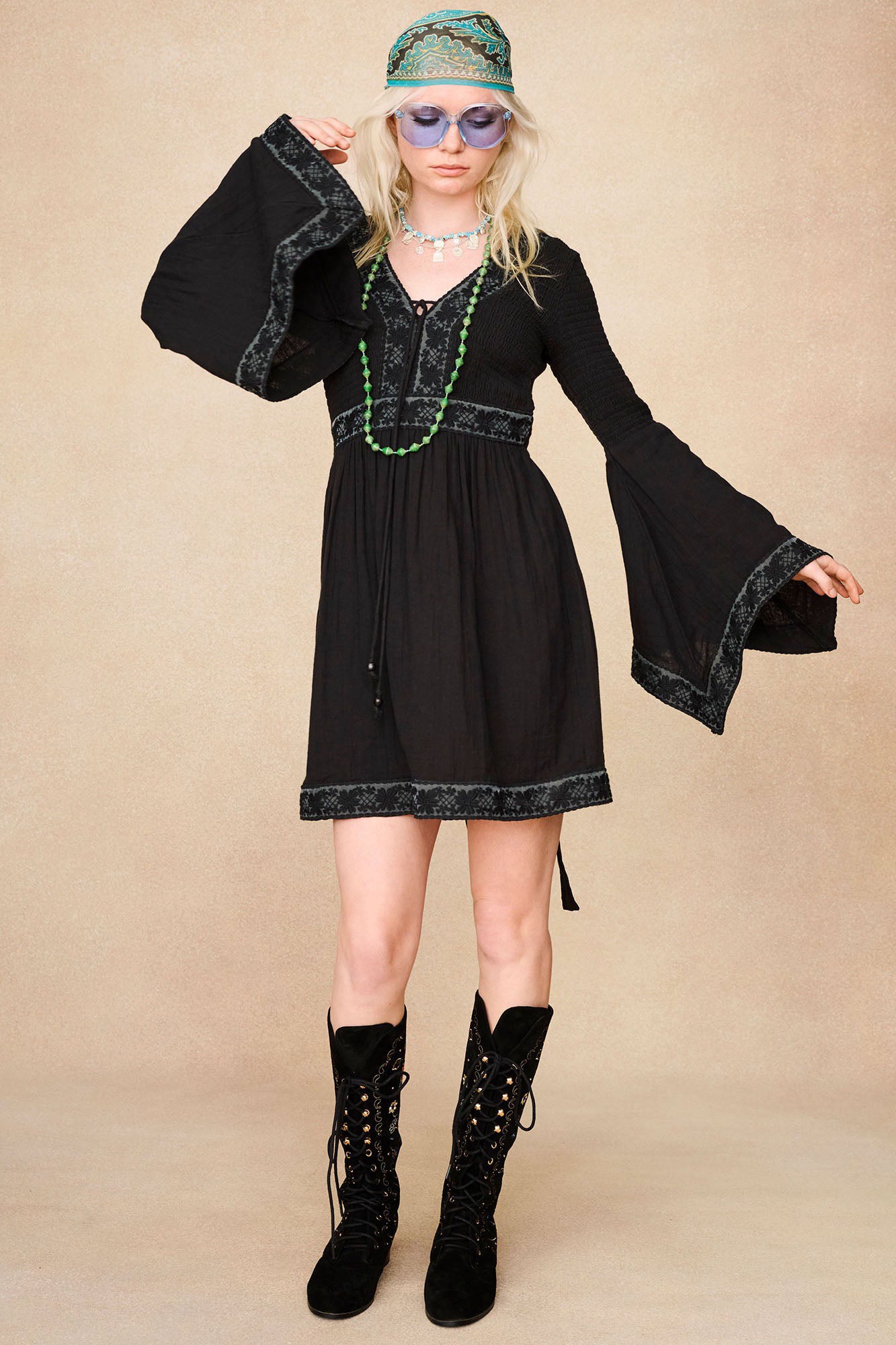 Full-length model shot featuring The Hippie Shake's black mini dress with lace trim styled with our black embroidered boots.