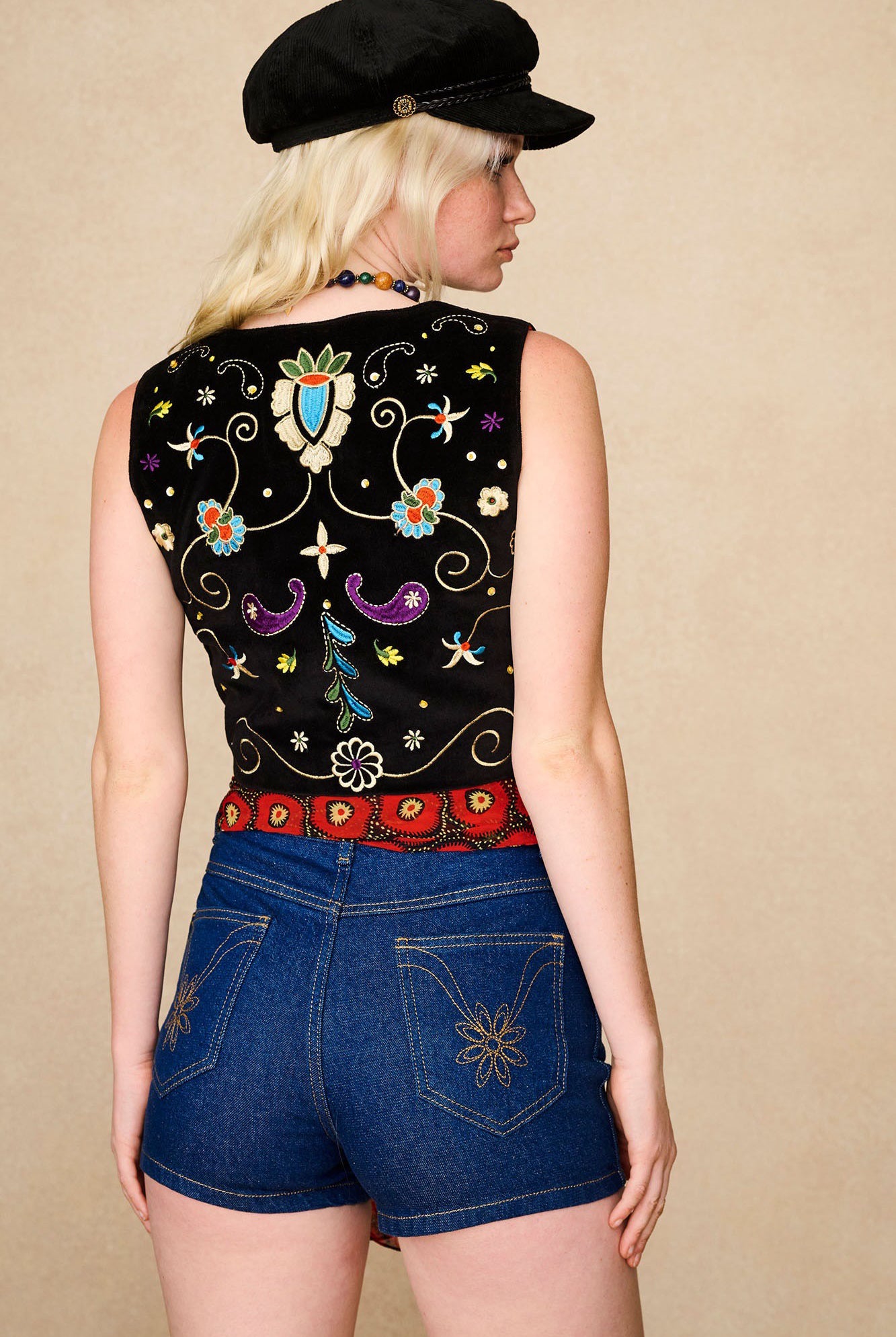 Model styling The Hippie Shake's vintage high waisted shorts with a red printed scarf and black embroidered vest.