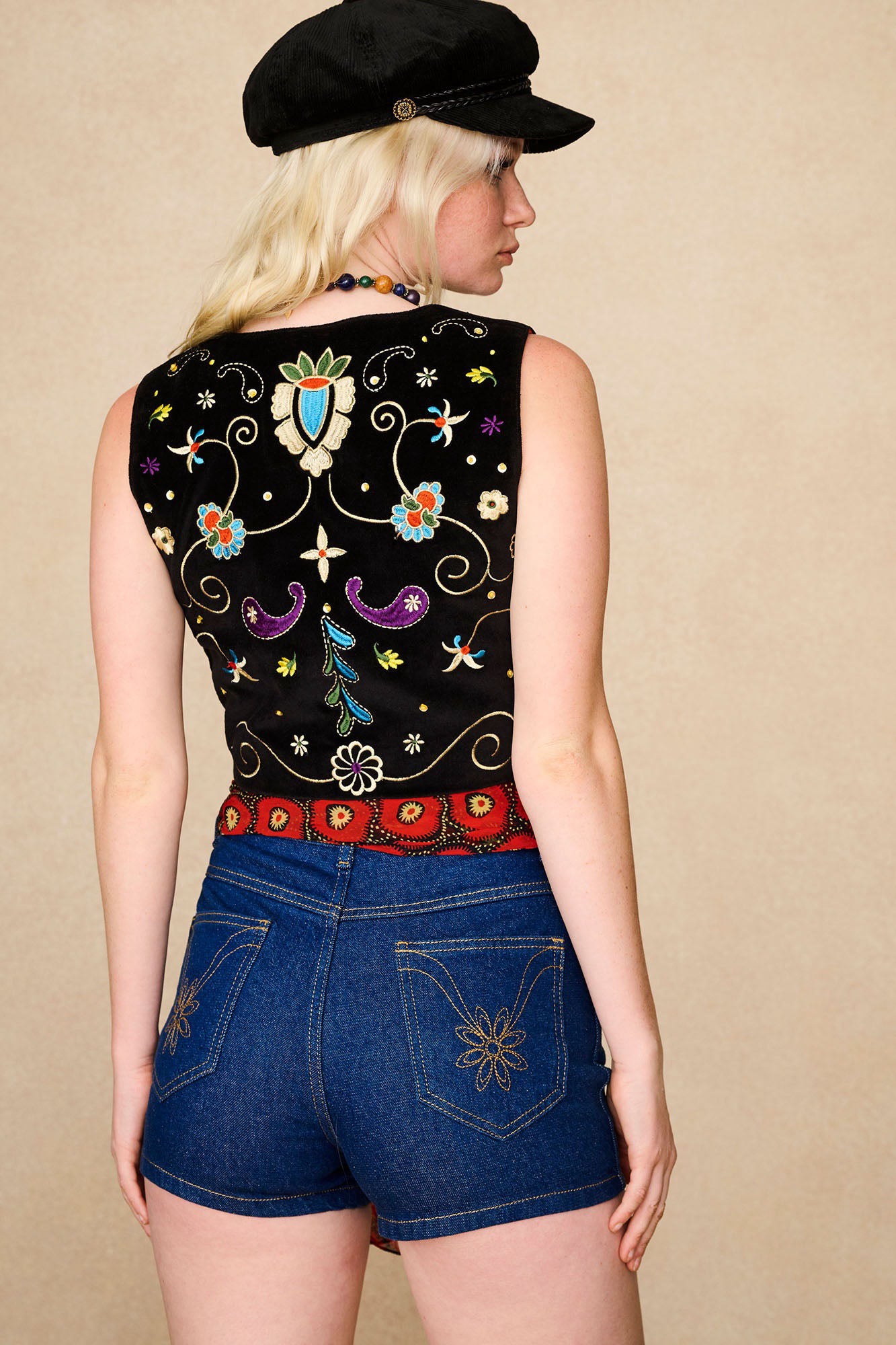Model styling The Hippie Shake's vintage high waisted shorts with a red printed scarf and black embroidered vest.