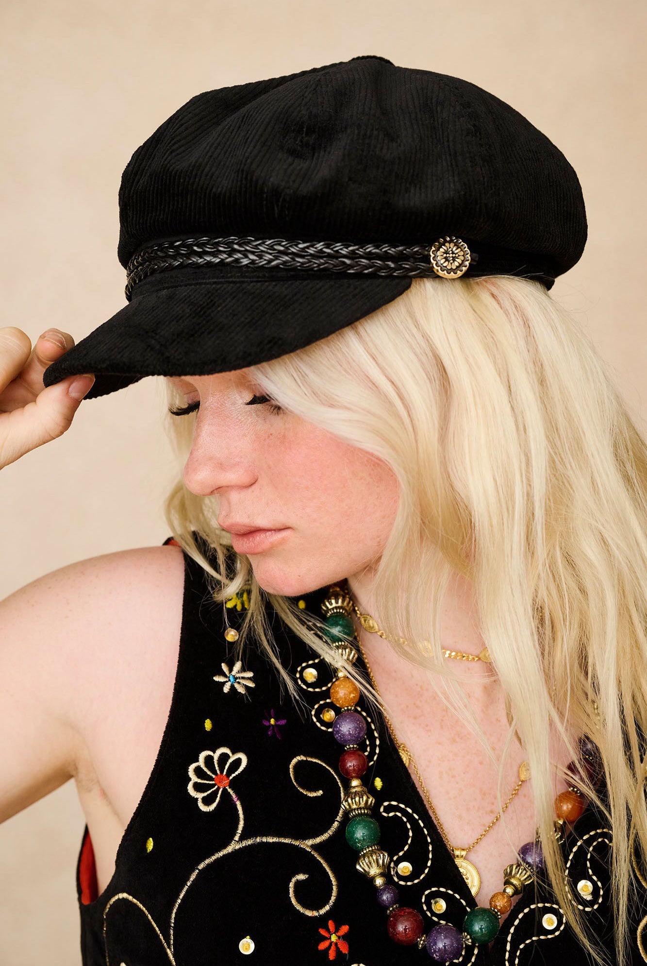 The Hippie Shake's corduroy baker hat shown in side profile worn with our vintage black velvet embroidered waistcoat.