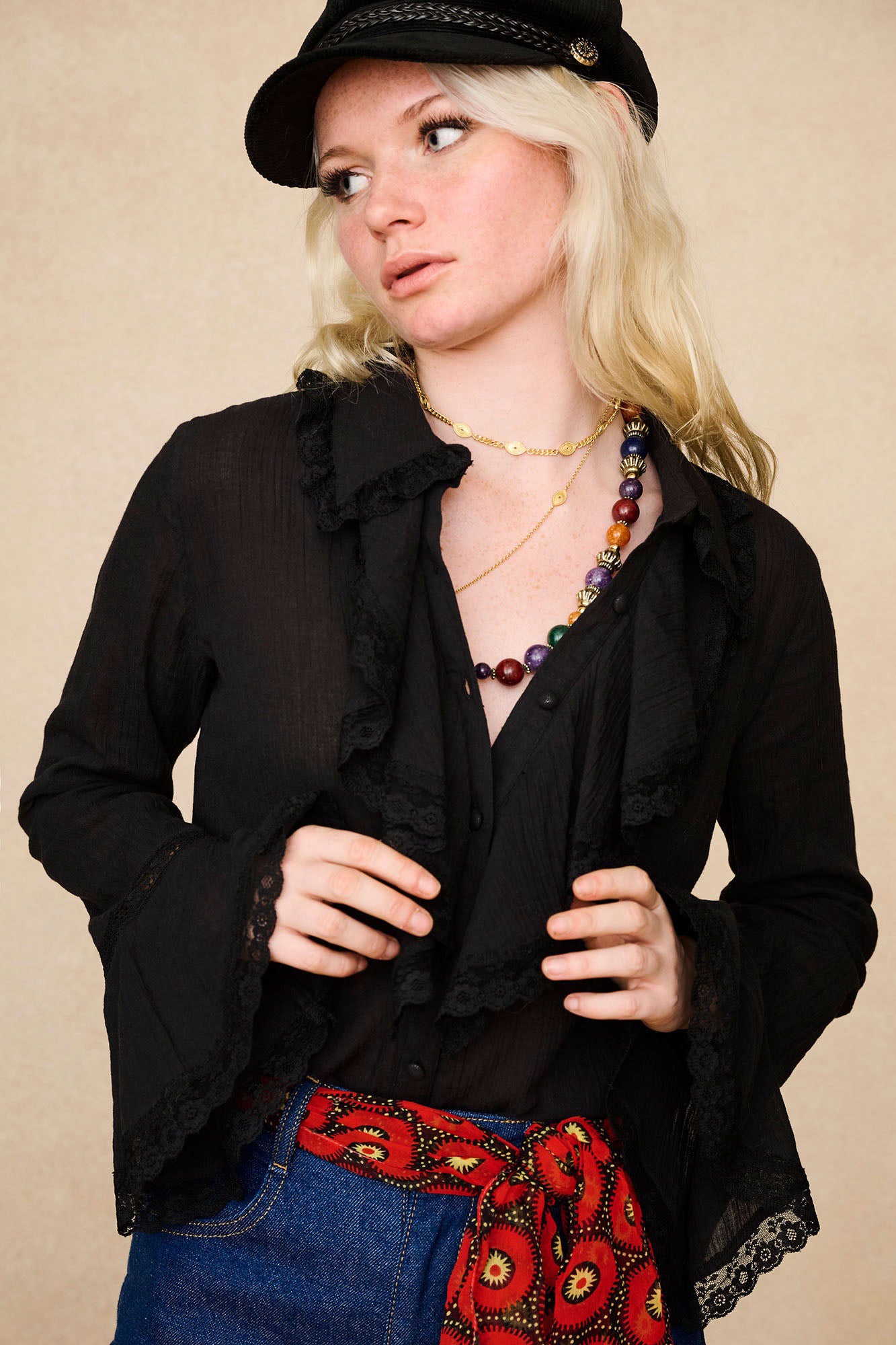 Close-up of model wearing The Hippie Shake's black ruffled blouse with lace trim, styled with our black baker hat.