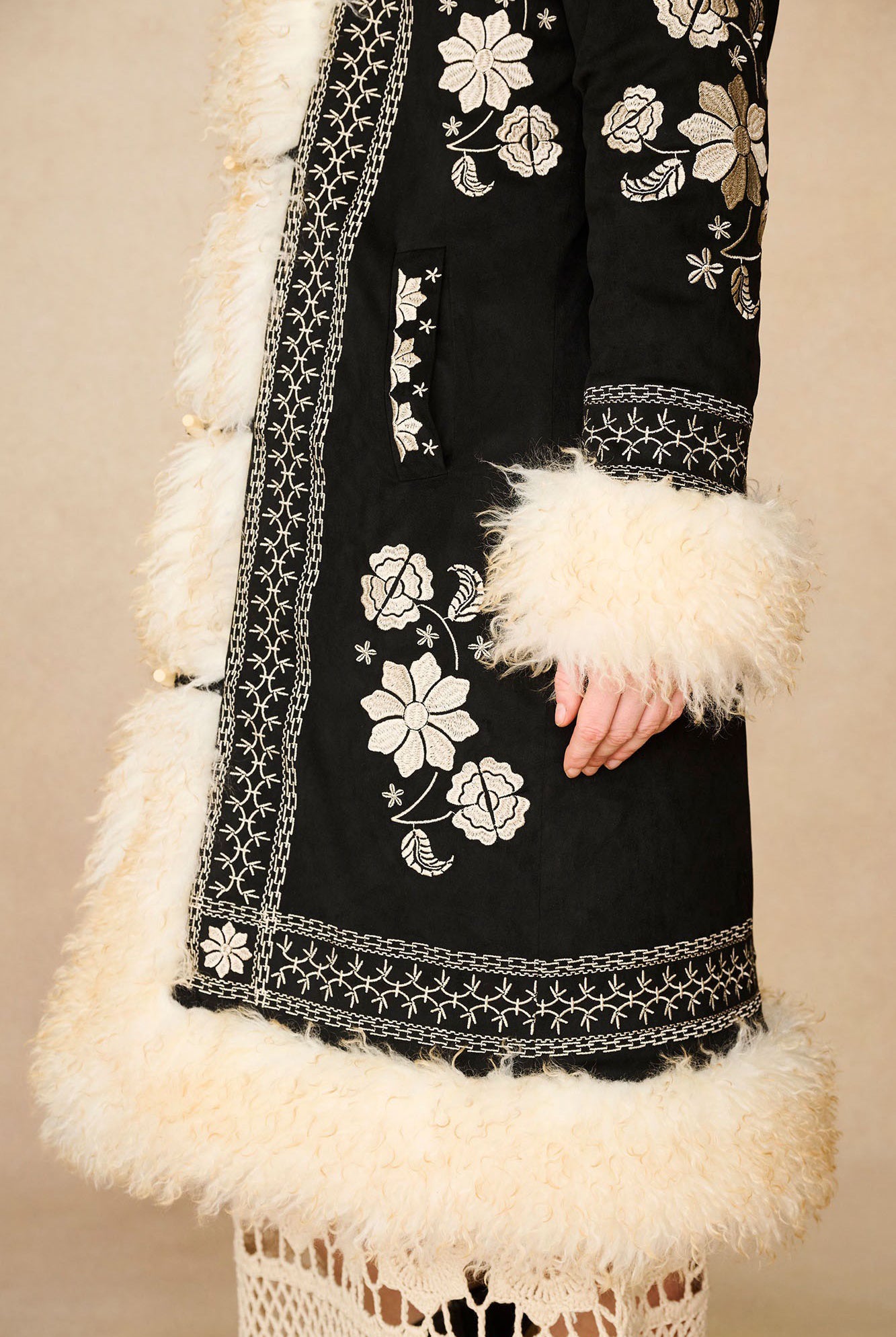 Side profile of The Hippie Shake's black embroidered Penny Lane coat featuring its soft off-white shaggy faux fur trims.