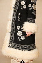 Side profile of The Hippie Shake's black embroidered Penny Lane coat featuring its soft off-white shaggy faux fur trims.