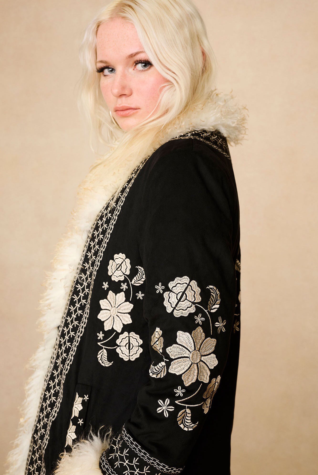 Side profile of The Hippie Shake's vintage inspired black afghan coat featuring the intricate embroidery down the sleeve.