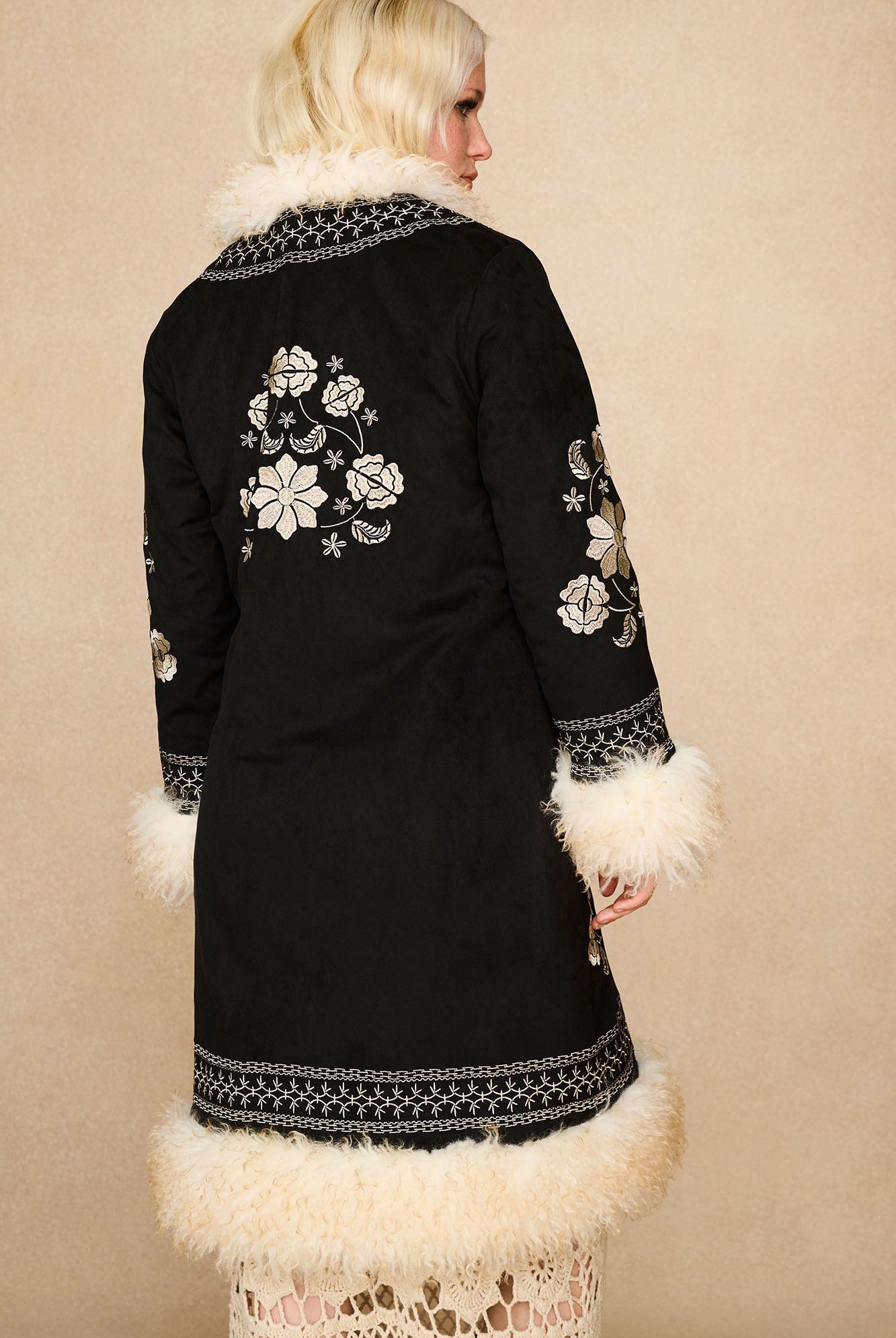The Hippie Shake's black embroidered Penny Lane coat seen from behind, featuring cream floral embroidery across the back and sleeves.