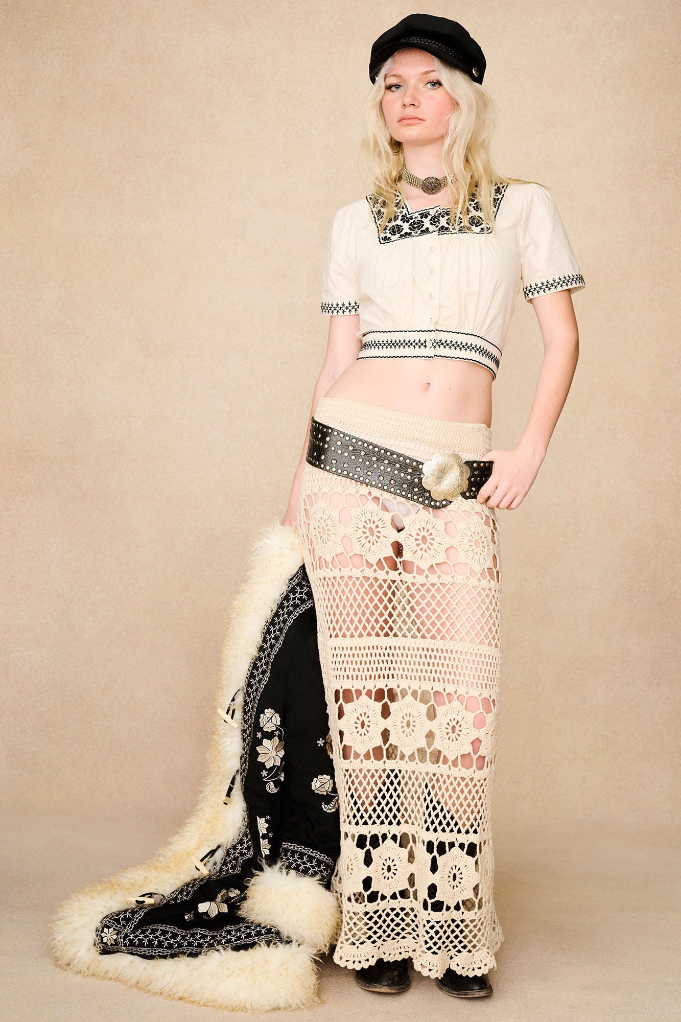 Styled with black cropped blouse, The Hippie Shake's cream crochet maxi skirt paired with black Penny Lane coat.