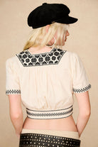 Back view of The Hippie Shake's cream embroidered floral crop top with floral embroidery and gathered hem.