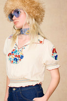 Side view of model in The Hippie Shake's brown faux fur hat with blue sunglasses, styled with our floral embroidered cream blouse.