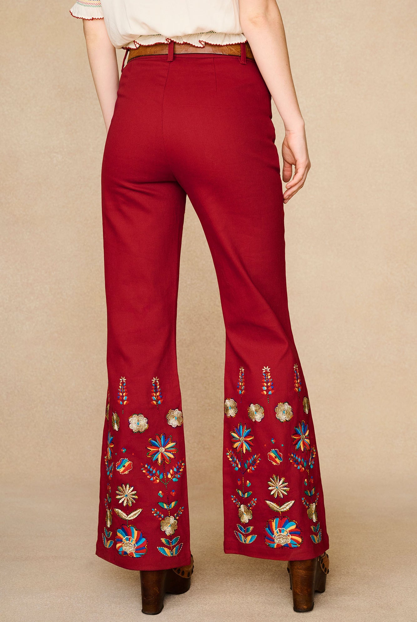 Back view of The Hippie Shake's red embroidered flared trousers highlighting the all-around embroidery at the hem.