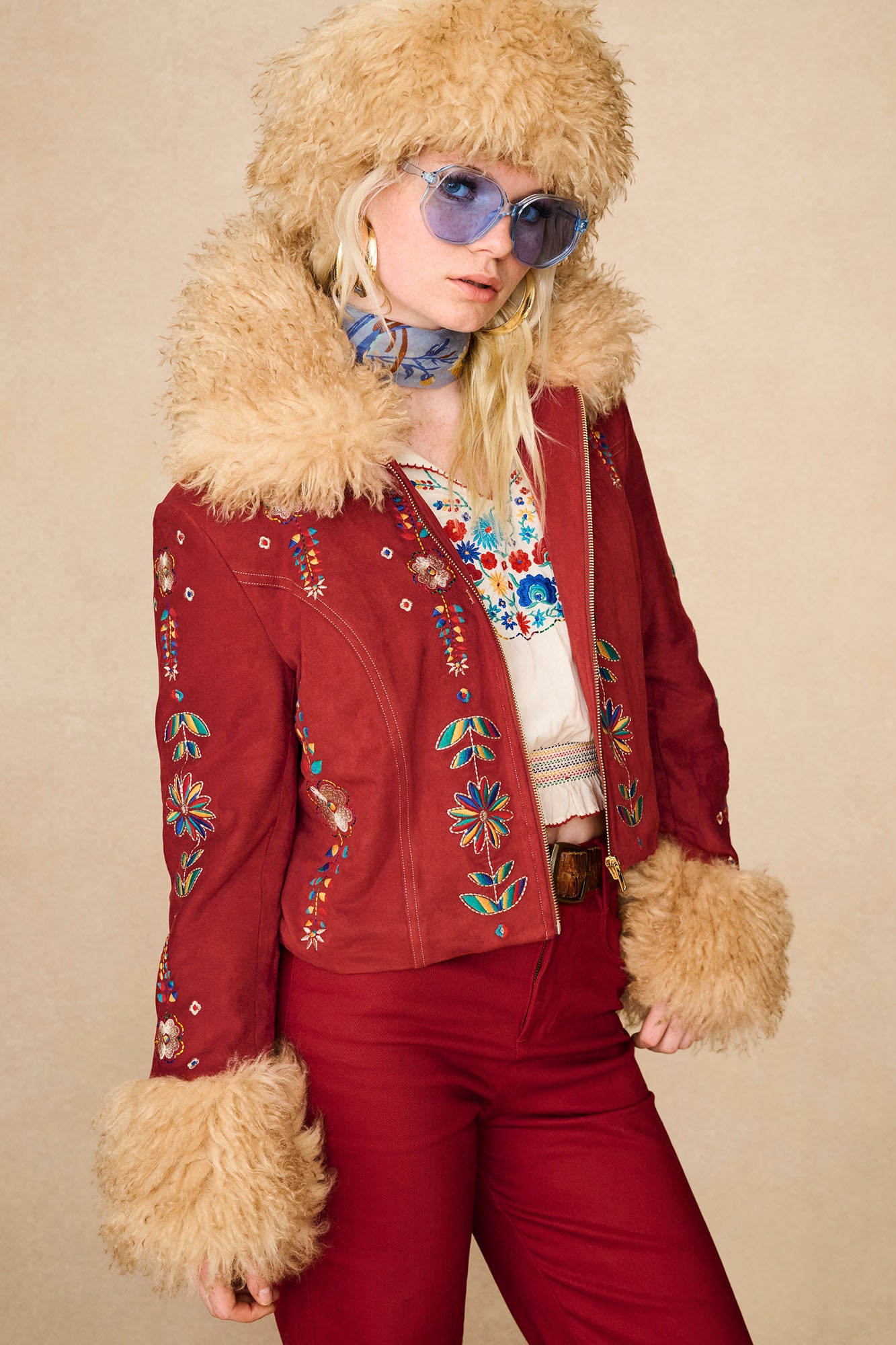 Model wearing The Hippie Shake's red embroidered Penny Lane coat with faux fur trims and vibrant multicolour floral detailing.