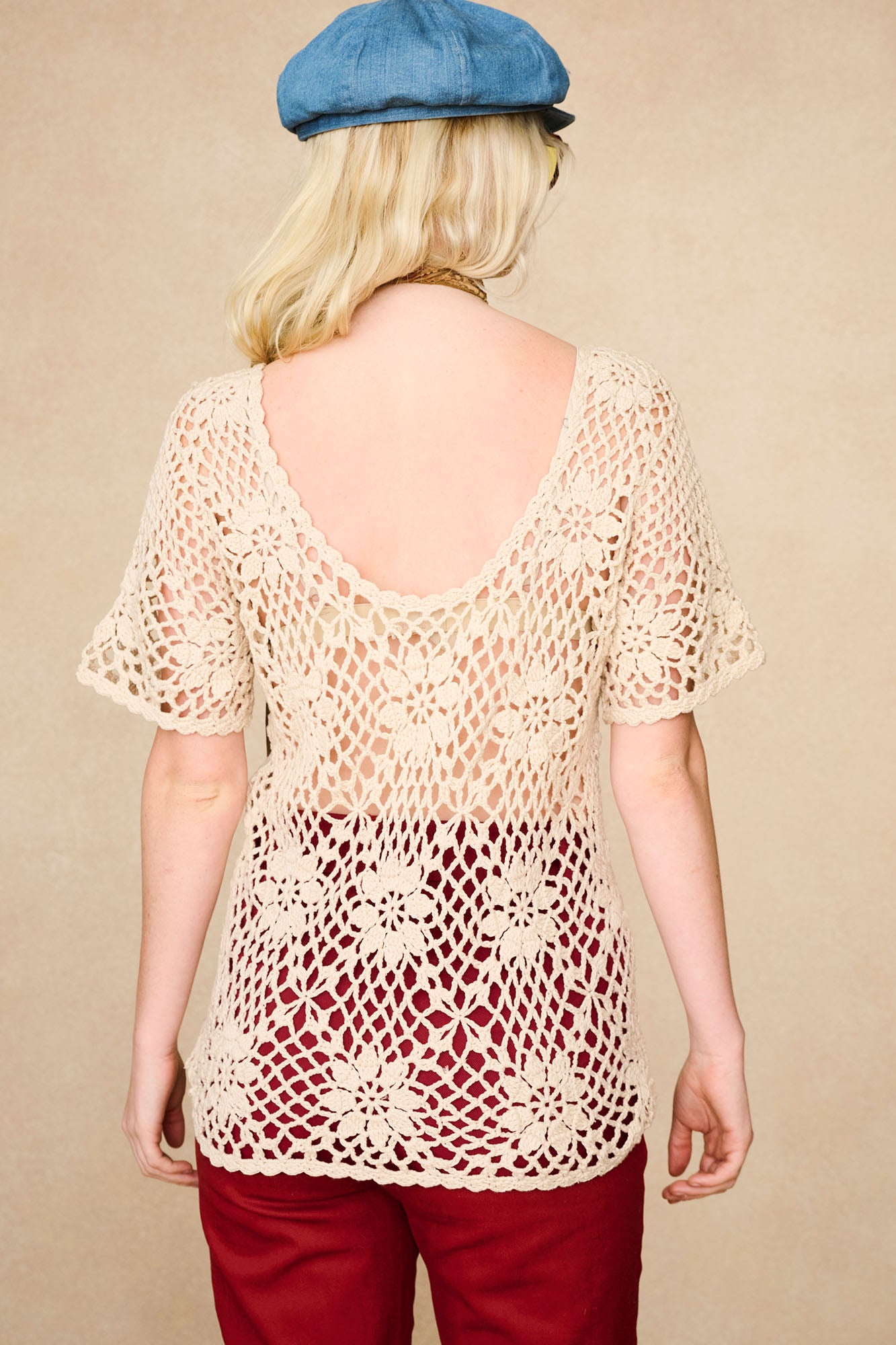 Back view of The Hippie Shake's cream floral crochet top showing low scoop neck and daisy crochet detail.