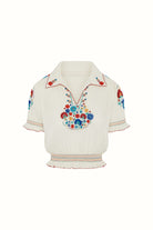 Flat lay of The Hippie Shake's cream floral Penny Lane blouse with red stitching and rainbow shirring.