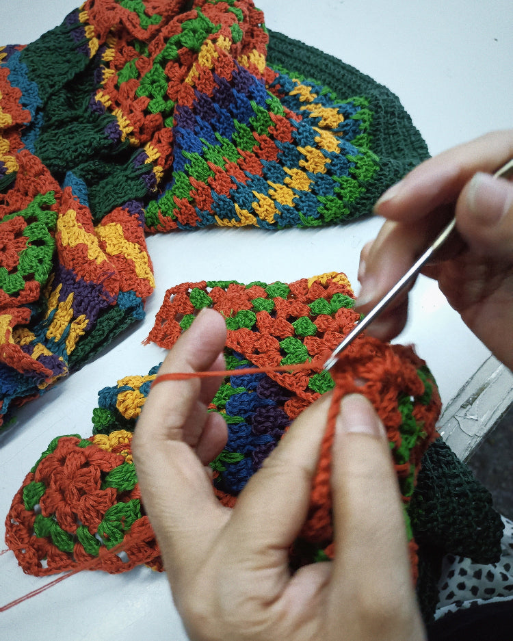 A close up of hands making The Hippie Shake's colourful crochet dress