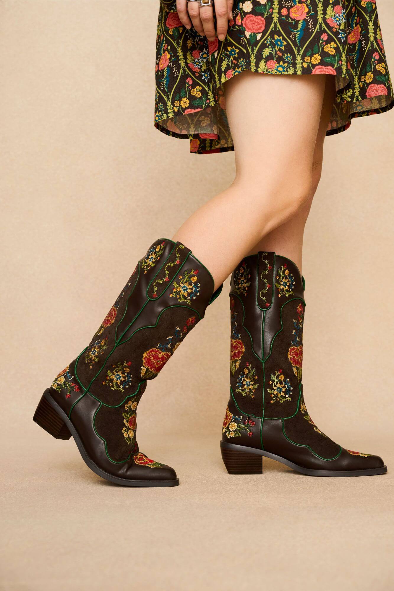 Brown Western style embroidered boots with floral patterns worn by a model on a beige background - other side view