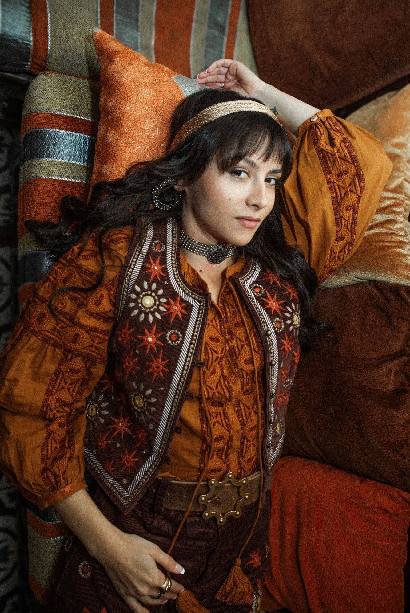 The Hippie Shake House of The Rising Sun collection - model laying down wearing orange embroidered blouse and embroidered vest