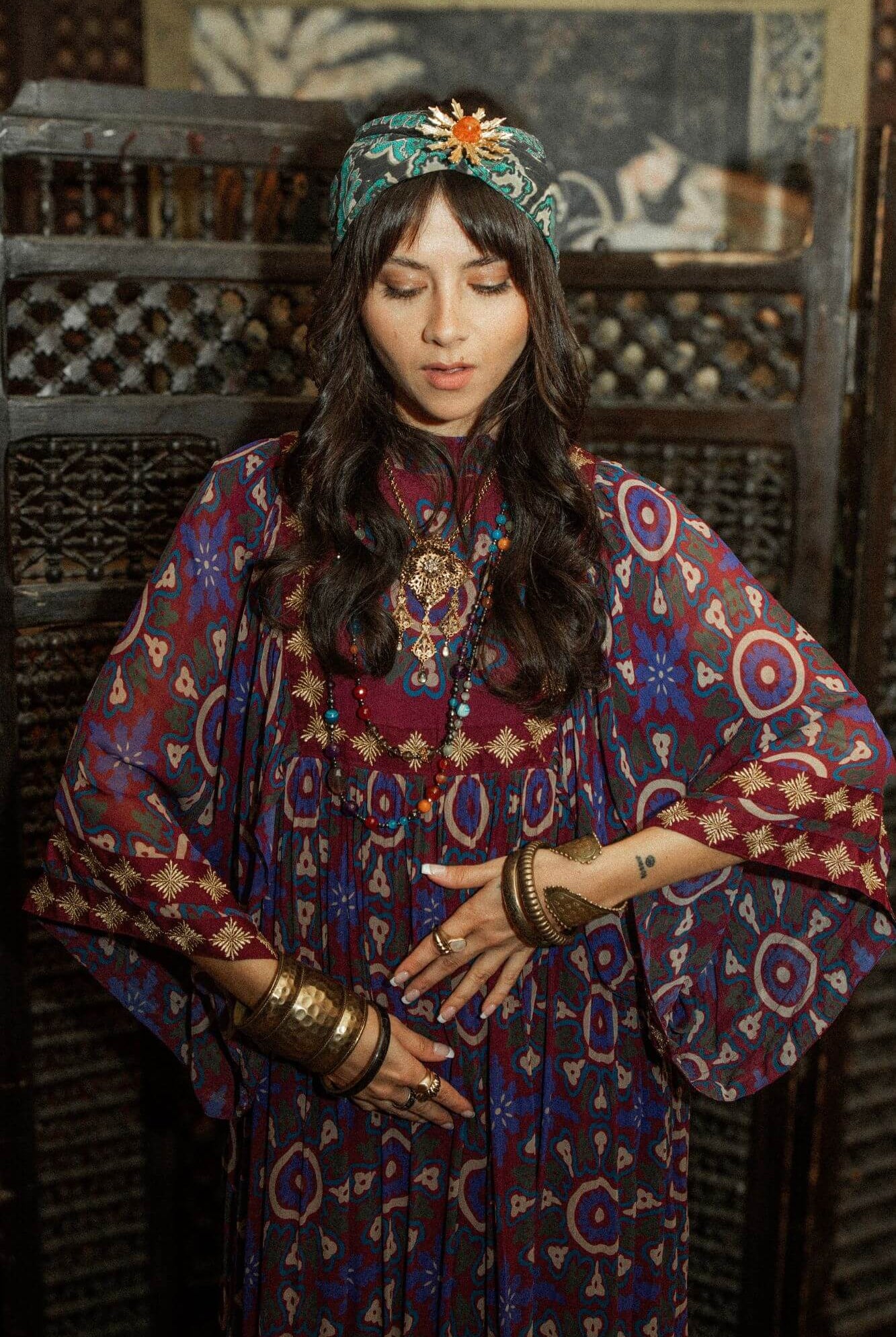 Model dancing wearing a 70s style bohemian maxi dress in a printed purple fabric with hand embroidery - close up