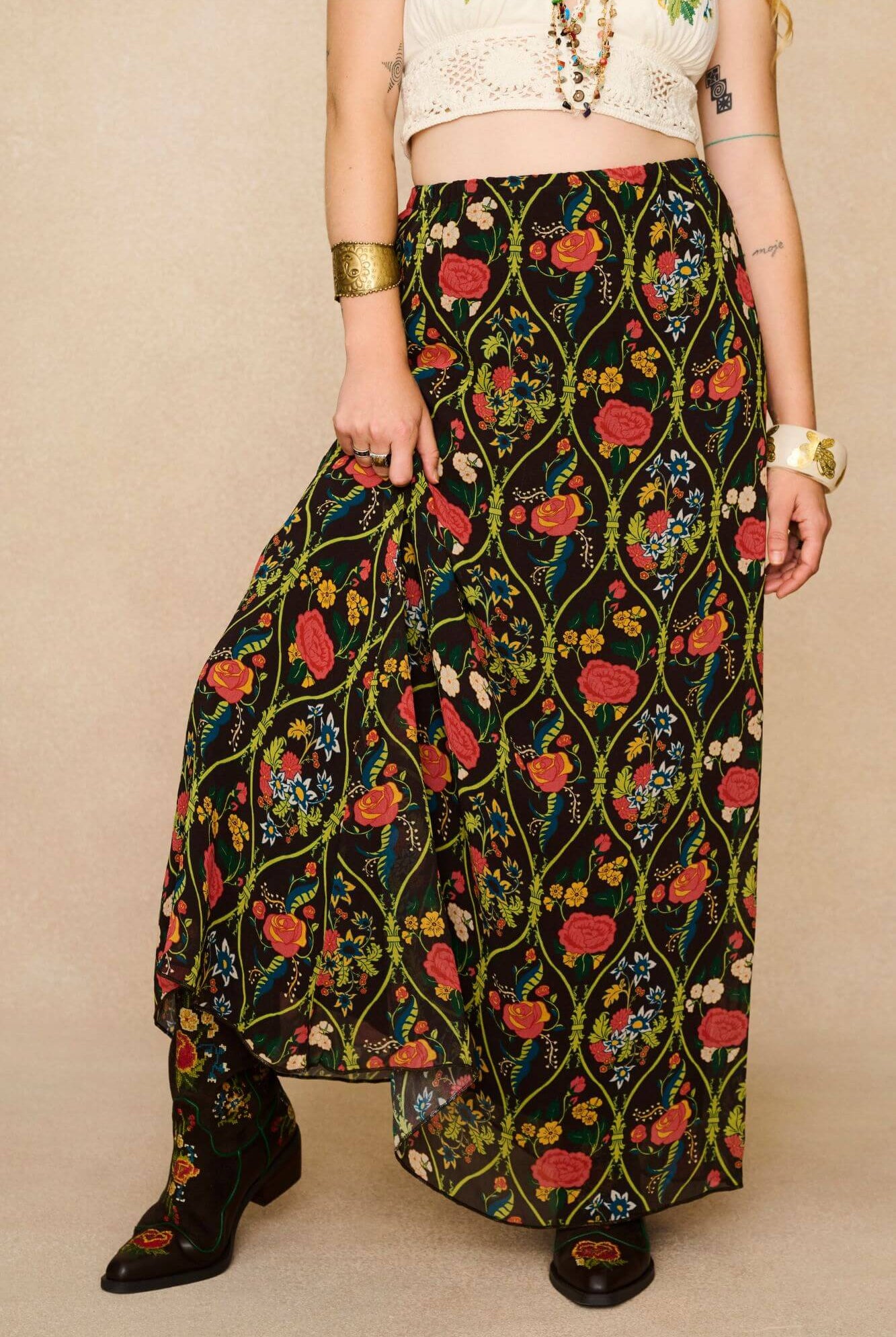 Model wearing a long 70s style floral skirt and white top with a beige background - close up