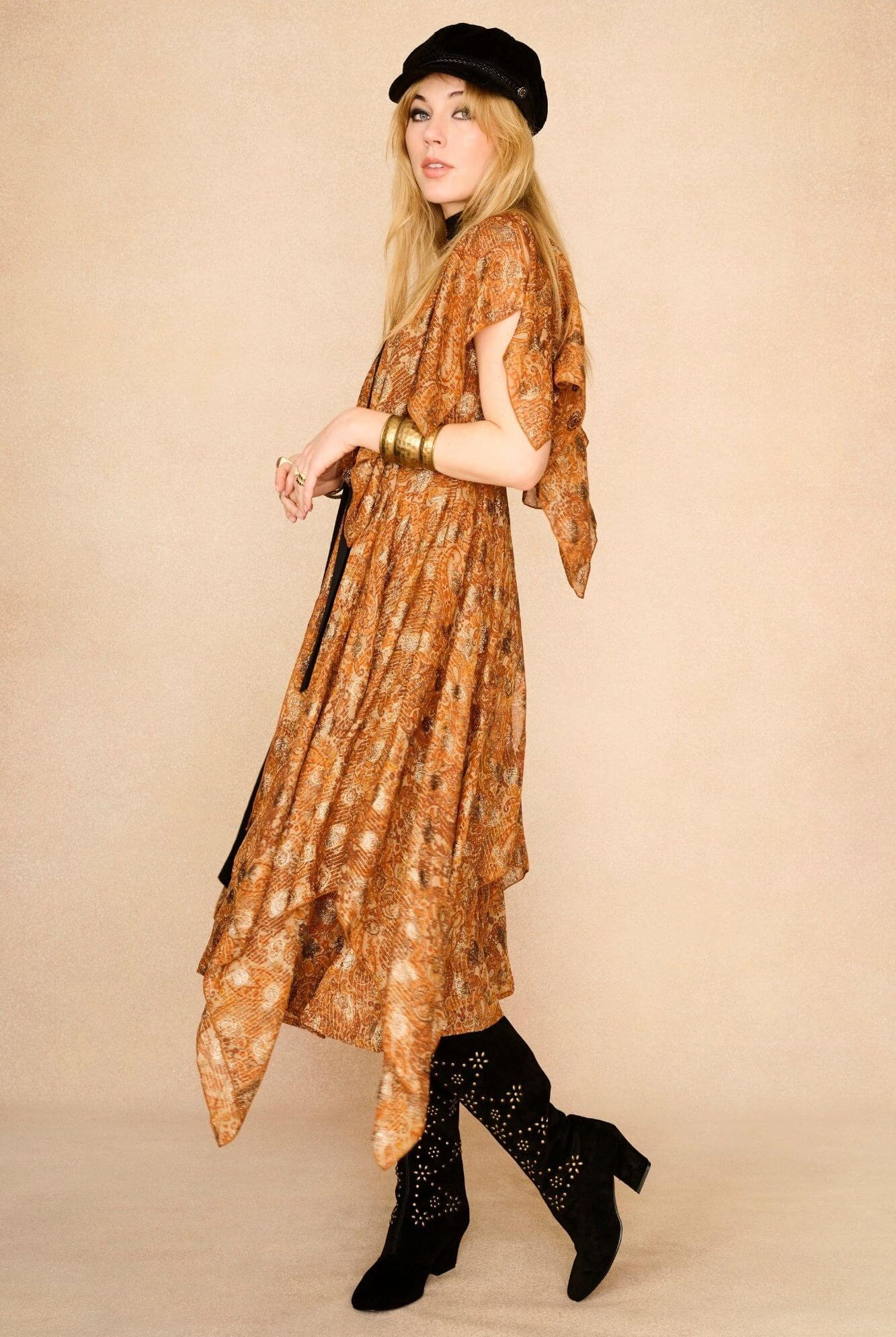 Model wearing a patterned dress and black 70s style suede boots with gold studs
