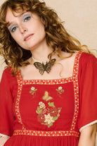Model wearing a red floaty maxi dress with embroidered details - close up of embroidery