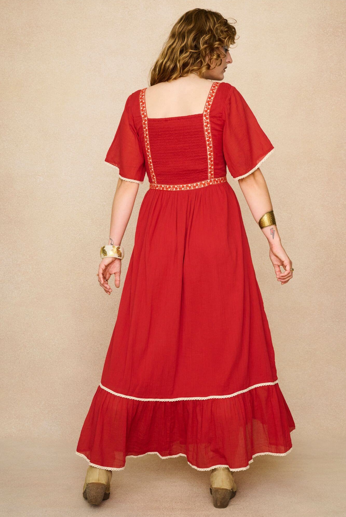 Model wearing a red floaty maxi dress with embroidered details - back view