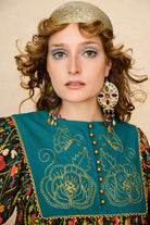 Model wearing a 70s style floral mini dress and matching boots against a beige background - front view close up