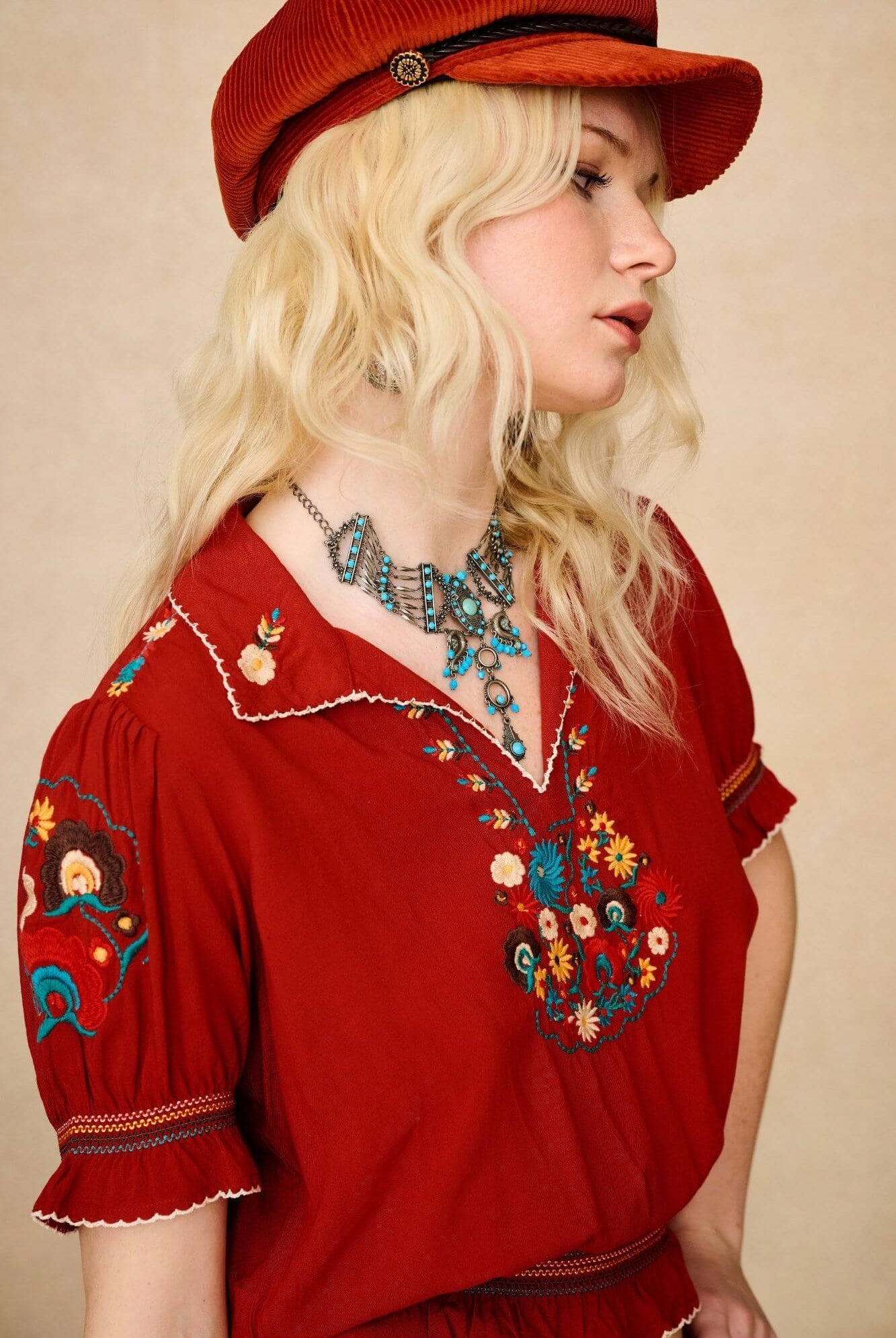 Model wears red floral embroidered Penny Lane blouse in soft cotton with shirred details. A vintage-inspired boho blouse made for everyday and festival styling by The Hippie Shake. Side view