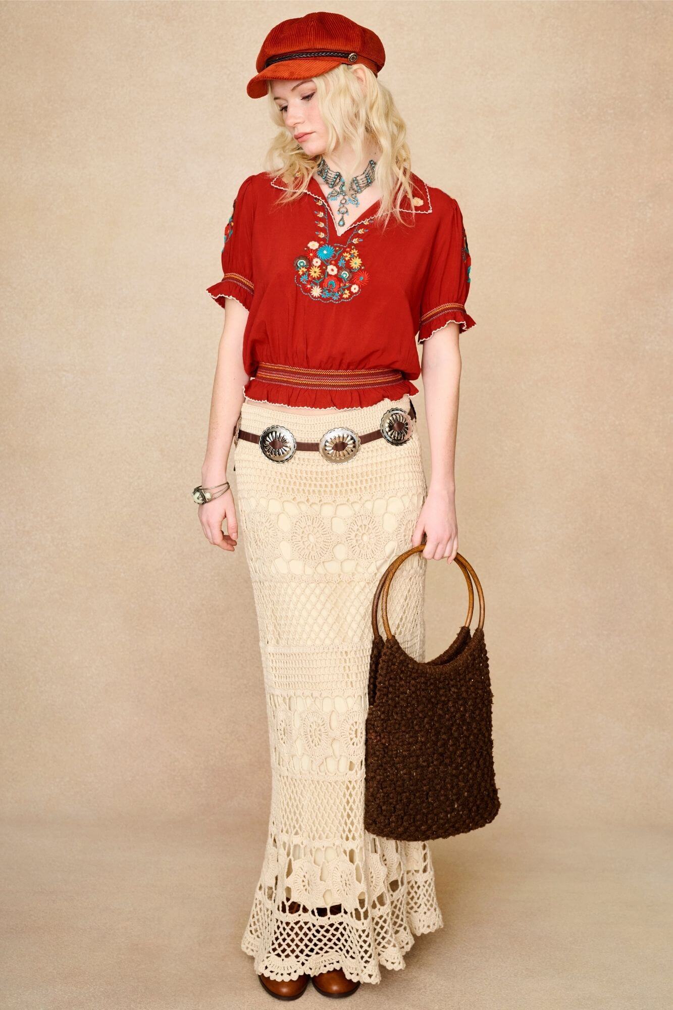 Model wears red floral embroidered Penny Lane blouse in soft cotton with shirred details. A vintage-inspired boho blouse made for everyday and festival styling by The Hippie Shake. Standing with crochet skirt