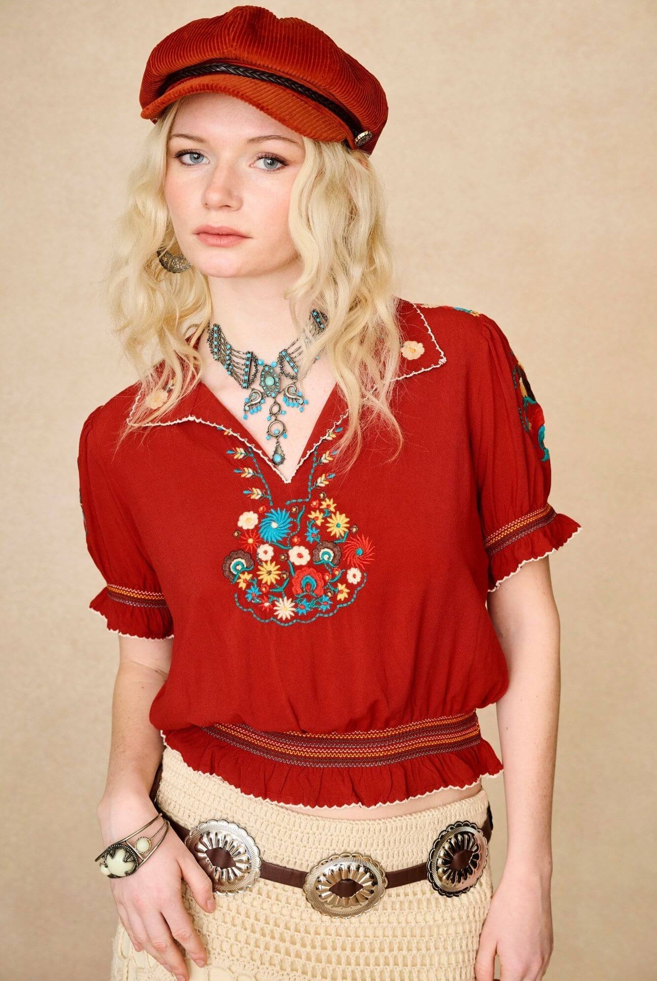 Model wears red floral embroidered Penny Lane blouse in soft cotton with shirred details. A vintage-inspired boho blouse made for everyday and festival styling by The Hippie Shake. Close up front view