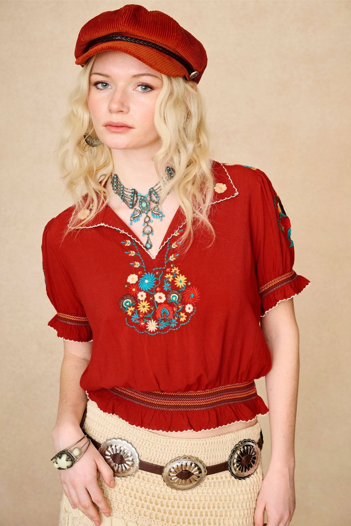 Model wears red floral embroidered Penny Lane blouse in soft cotton with shirred details. A vintage-inspired boho blouse made for everyday and festival styling by The Hippie Shake. Close up front view