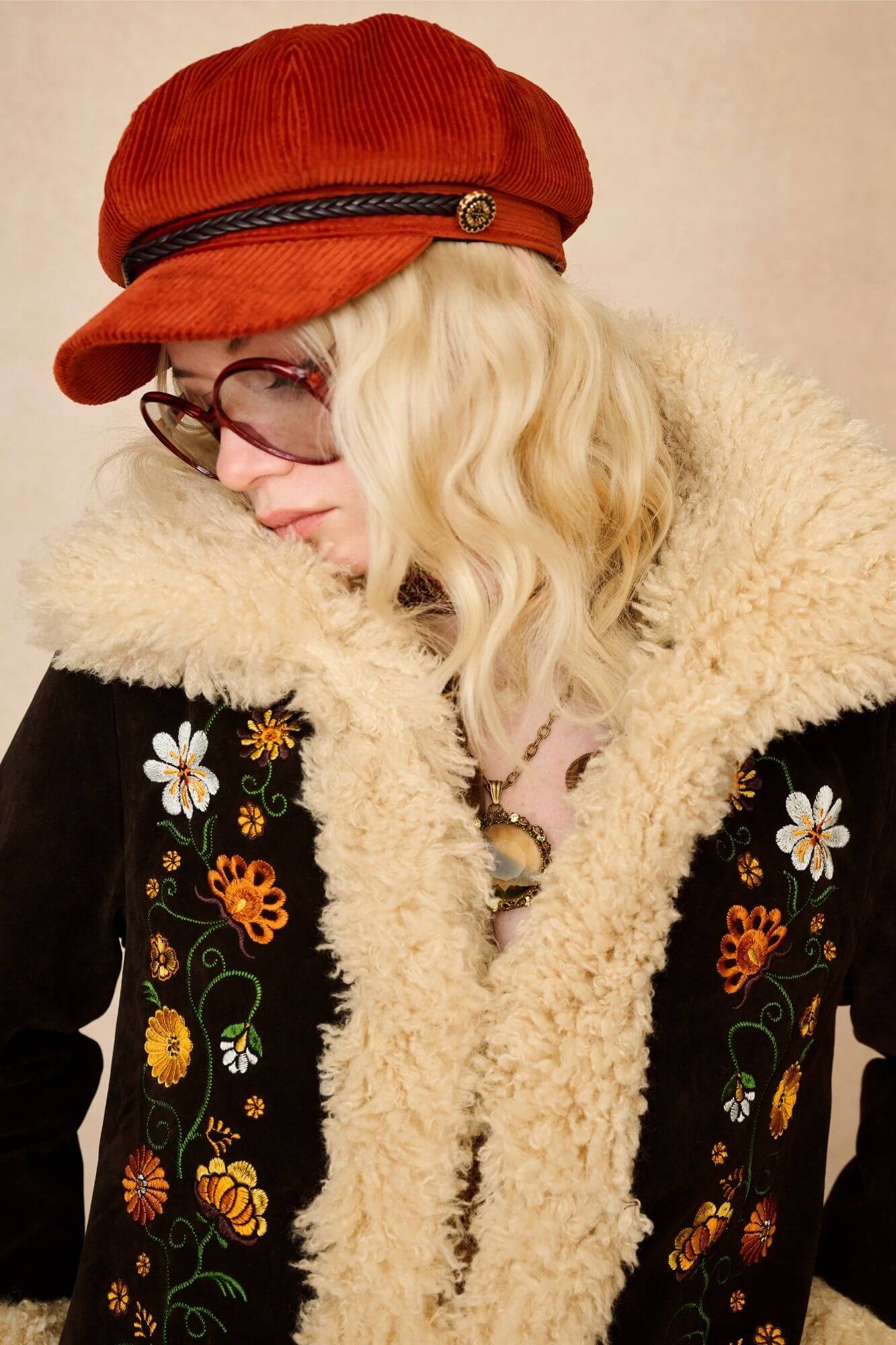 Model wears dark brown embroidered Penny Lane coat in faux suede with faux fur trim. A 70s-inspired statement coat made for bold, vintage boho styling by The Hippie Shake - close up view