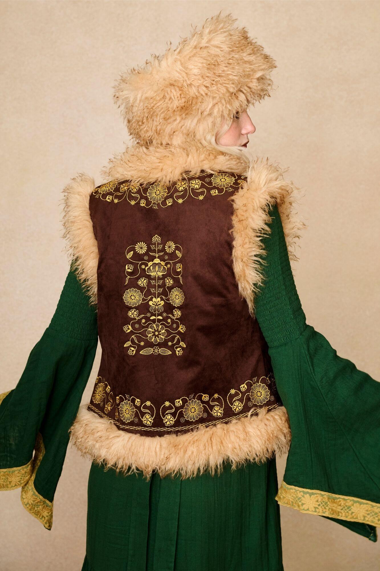 Model wears brown embroidered Penny Lane vest in faux suede with faux fur trim. A 70s-inspired boho layering piece made for vintage and festival styling by The Hippie Shake - back view