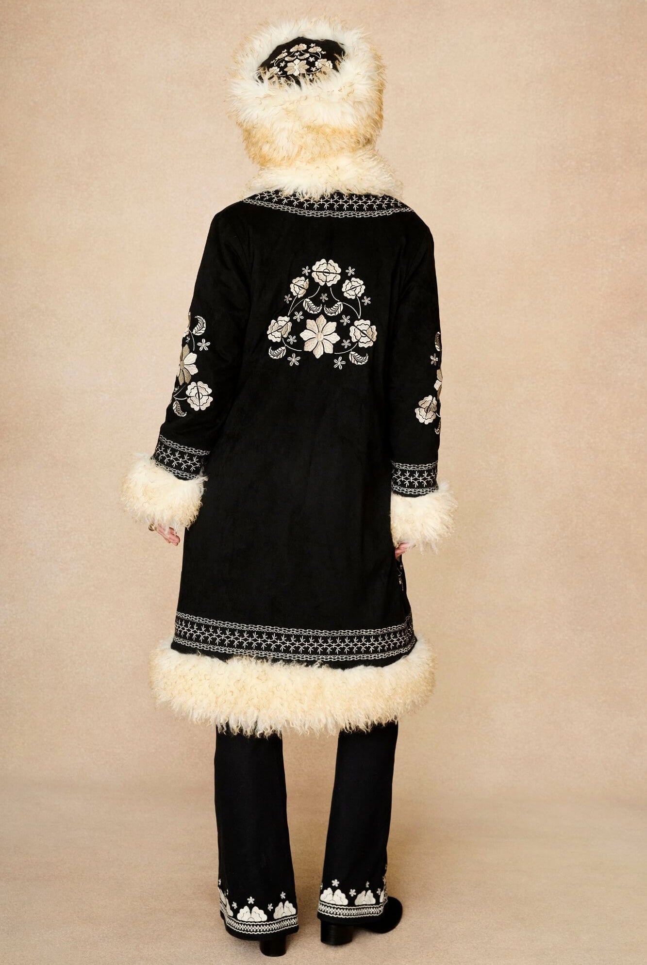 Model wears cream faux fur hat with vintage detailing and embroidered finish. A 70s-inspired boho winter hat made for statement styling by The Hippie Shake - back view with Black Penny Lane coat