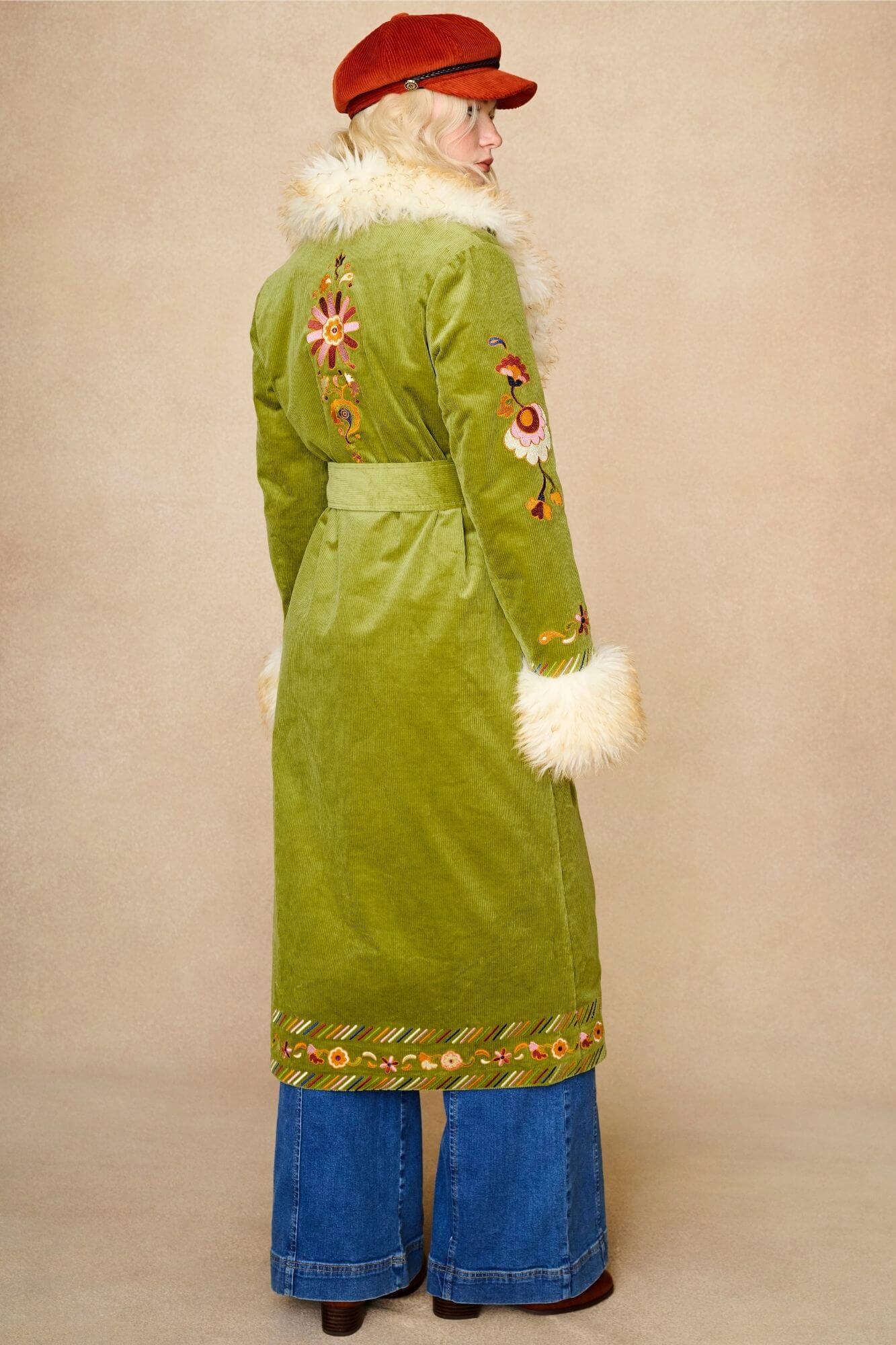 Model wears green embroidered Penny Lane coat in cotton corduroy with faux fur trim. A 70s-inspired statement coat made for bohemian, vintage styling by The Hippie Shake - back side view