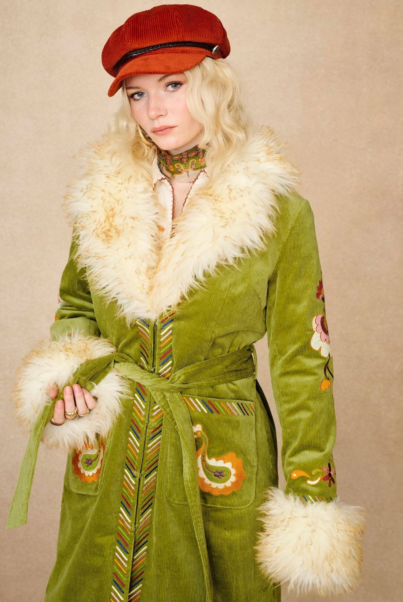 Model wears green embroidered Penny Lane coat in cotton corduroy with faux fur trim. A 70s-inspired statement coat made for bohemian, vintage styling by The Hippie Shake - front close up