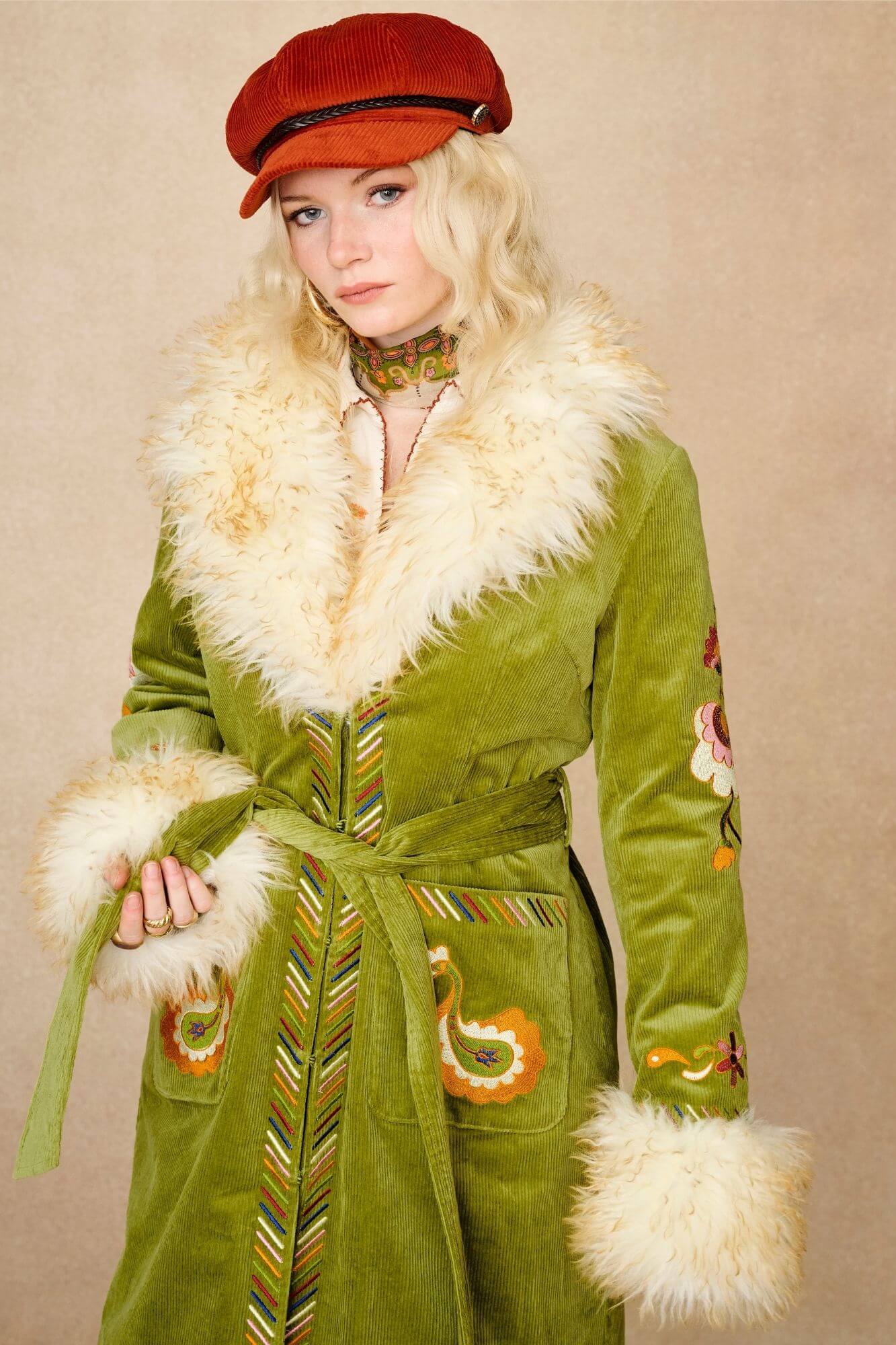 Model wears green embroidered Penny Lane coat in cotton corduroy with faux fur trim. A 70s-inspired statement coat made for bohemian, vintage styling by The Hippie Shake - front close up